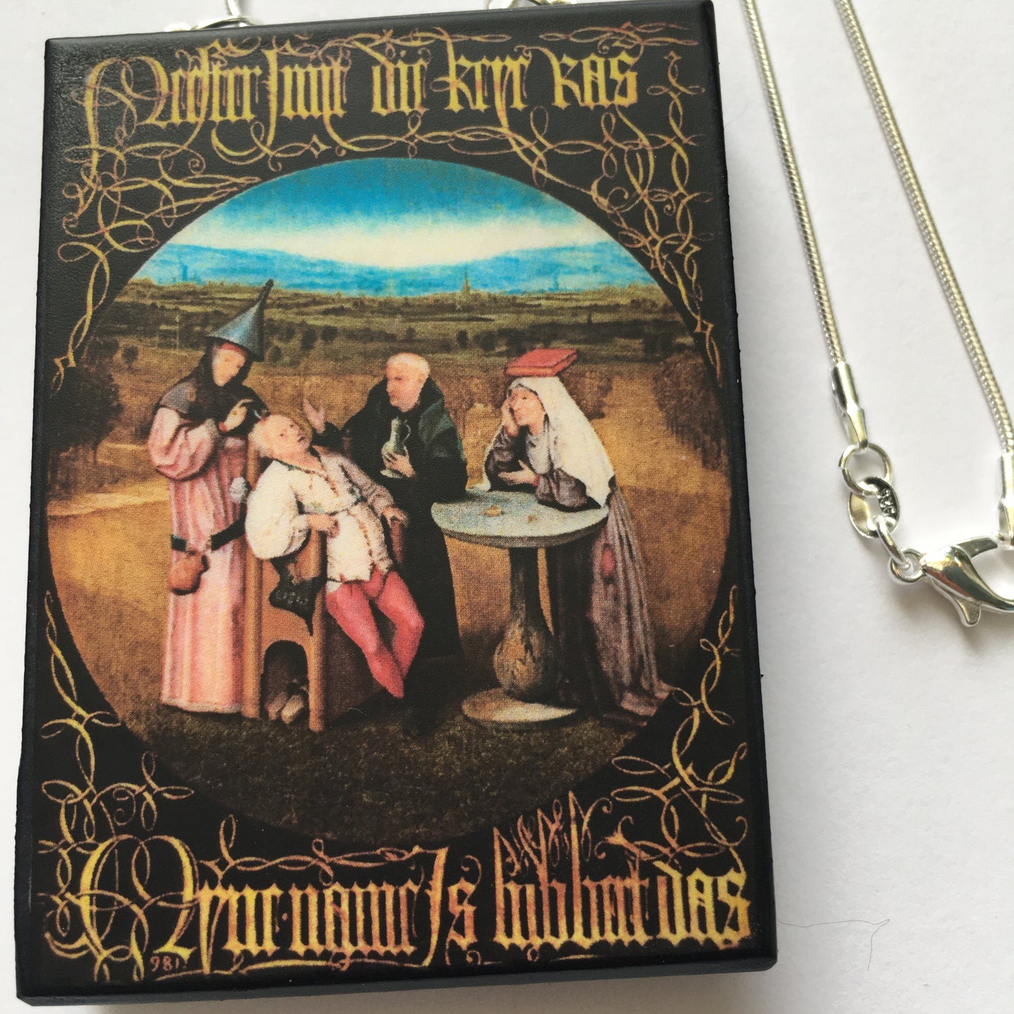 Hieronymus Bosch painting Cutting the Stone on top of this sustainable wood pendant with 925 sterling silver snake chain.
