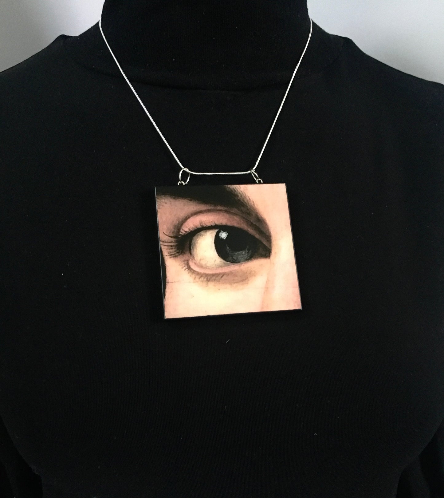 Sustainable wood pendant with an eye detail taken from a Renaissance art painting by Antonello da Messina. Handmade by Obljewellery