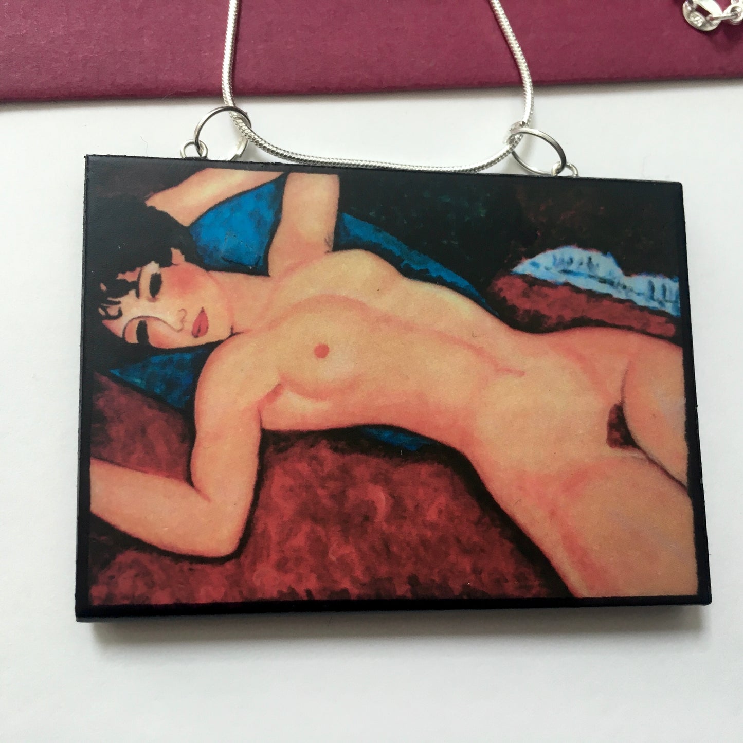 Amedeo Modigliani necklace handmade from sustainable wood by Obljewellery. The statement rectangular pendant with the painting of the nude female reclining on a red sofa on the blue cushion.