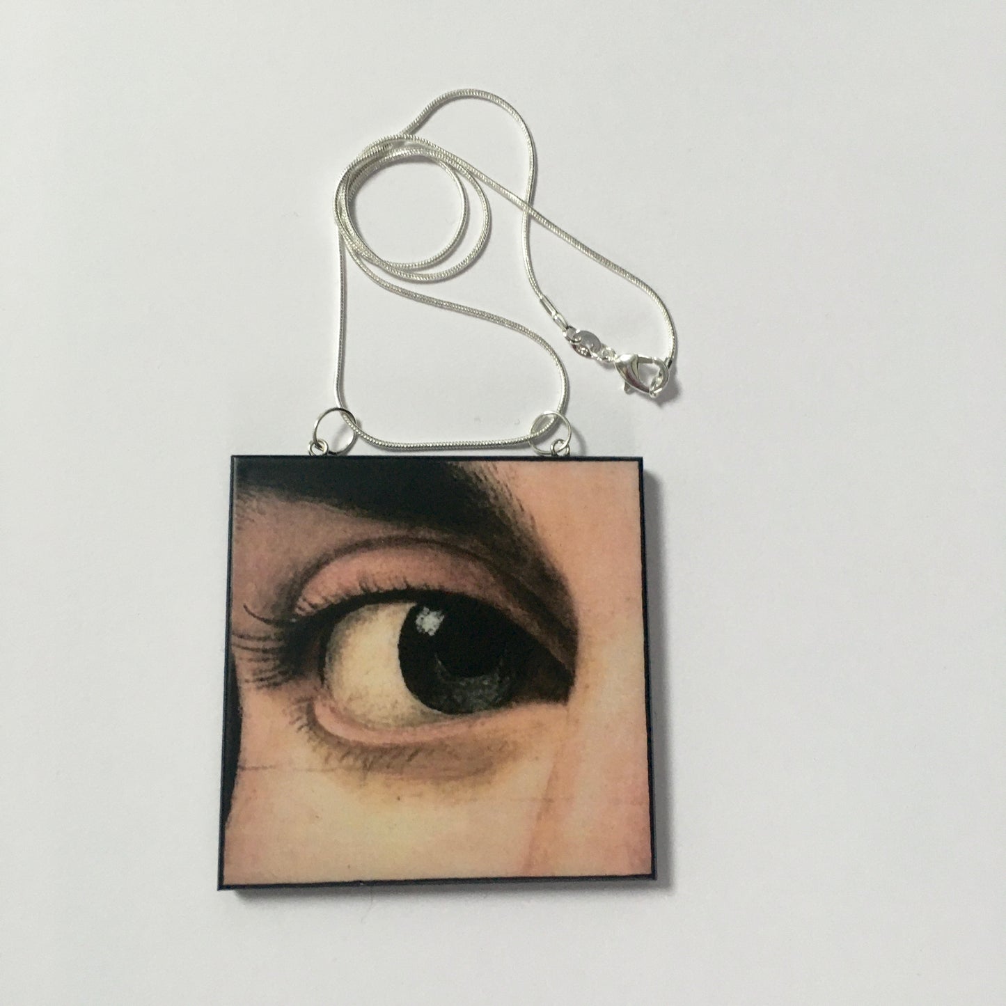 Sustainable wood pendant with an eye detail taken from a Renaissance art painting by Antonello da Messina. Handmade by Obljewellery