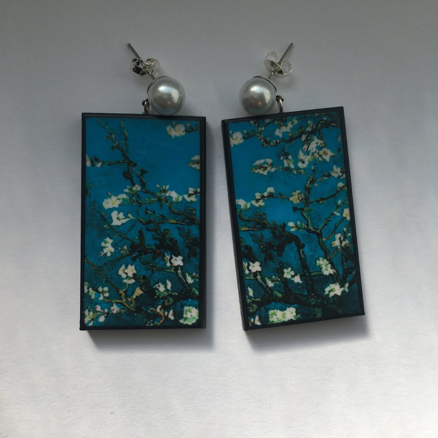 Stud pearls earrings with an art detail of the painting Almond Blossom by Vincent Van Gogh. These rectangular, turquoise background earrings are handmade from sustainable wood by Obljewellery.