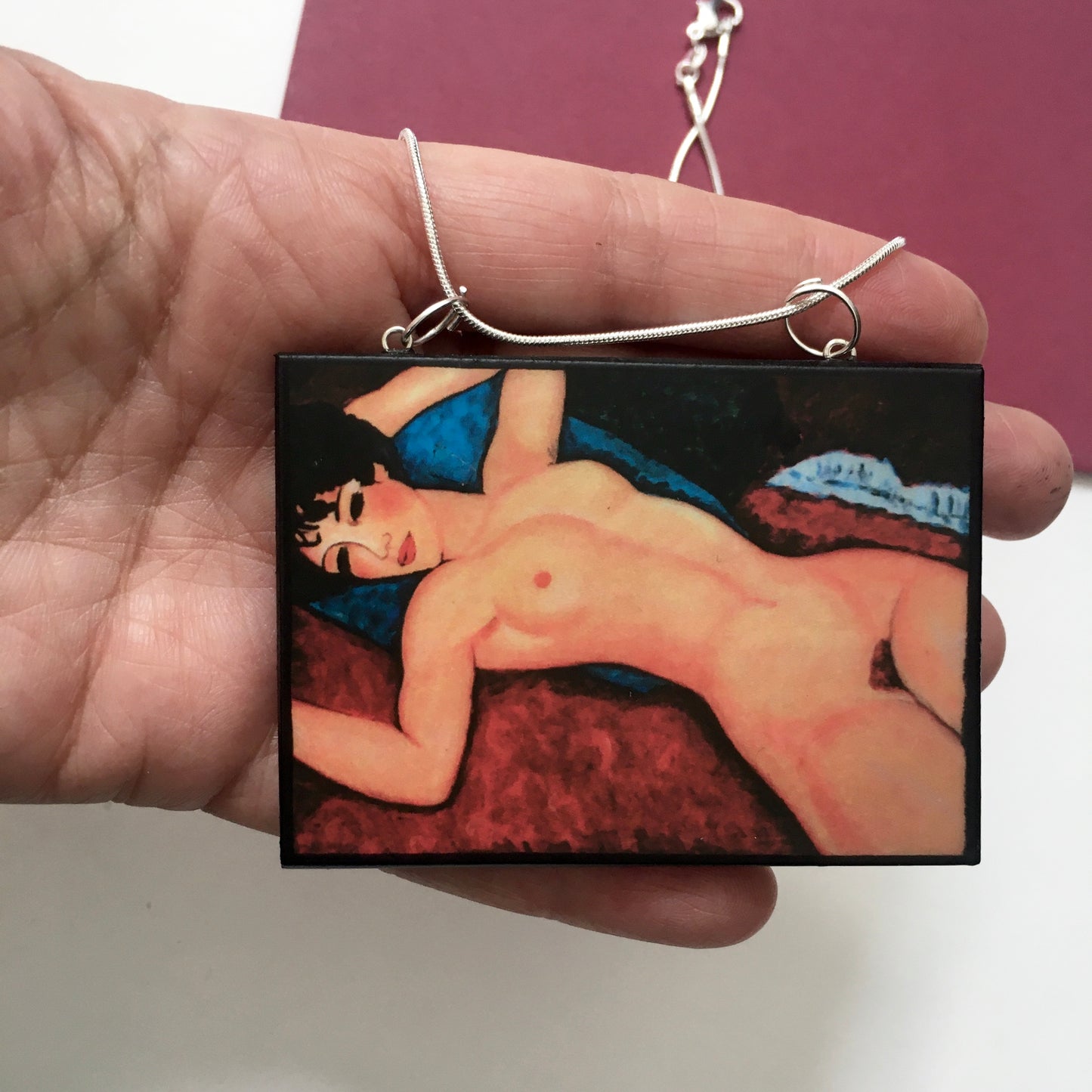 Amedeo Modigliani necklace handmade from sustainable wood by Obljewellery. The statement rectangular pendant with the painting of the nude female reclining on a red sofa on the blue cushion.