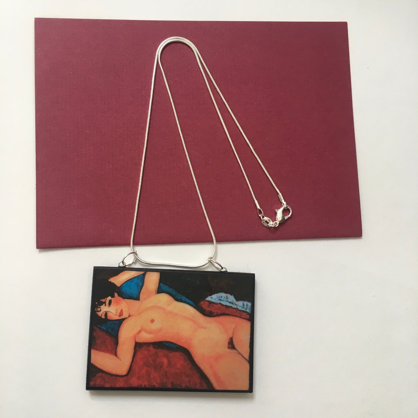 Amedeo Modigliani necklace handmade from sustainable wood by Obljewellery. The statement rectangular pendant with the painting of the nude female reclining on a red sofa on the blue cushion.