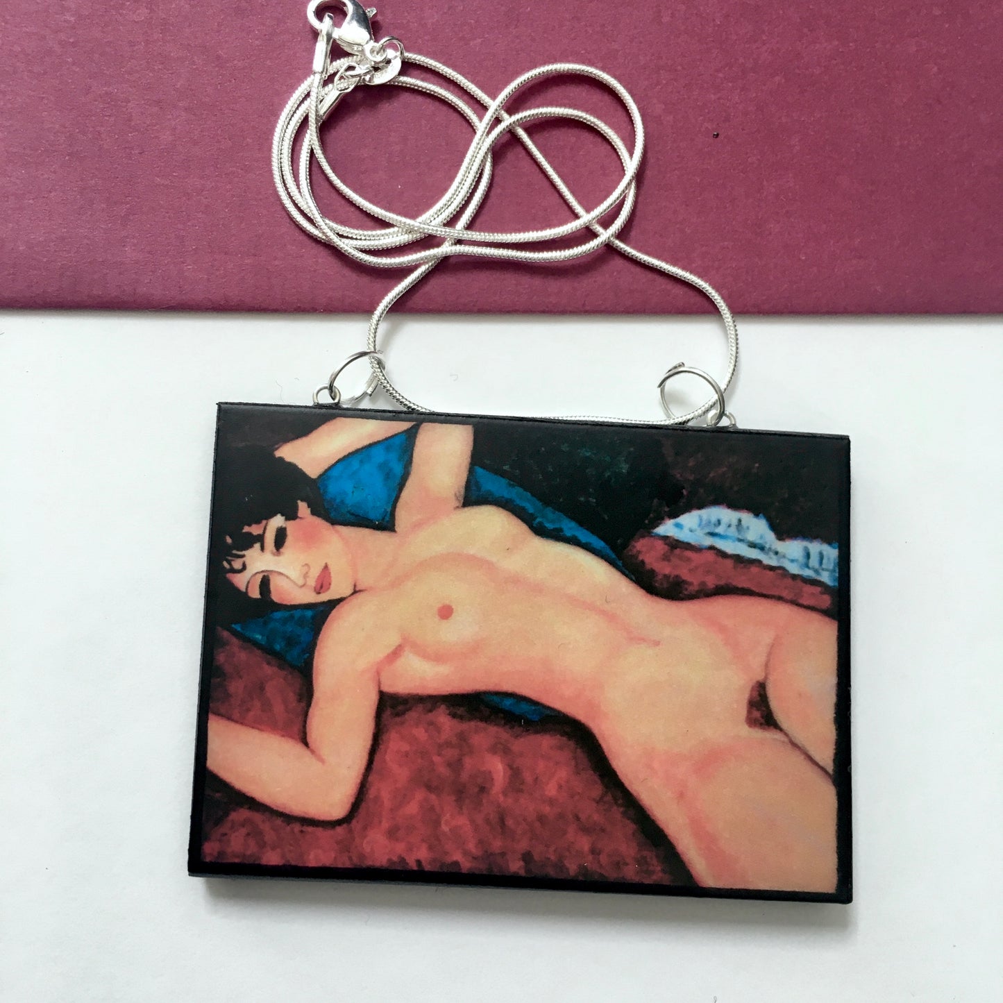 Amedeo Modigliani necklace handmade from sustainable wood by Obljewellery. The statement rectangular pendant with the painting of the nude female reclining on a red sofa on the blue cushion.