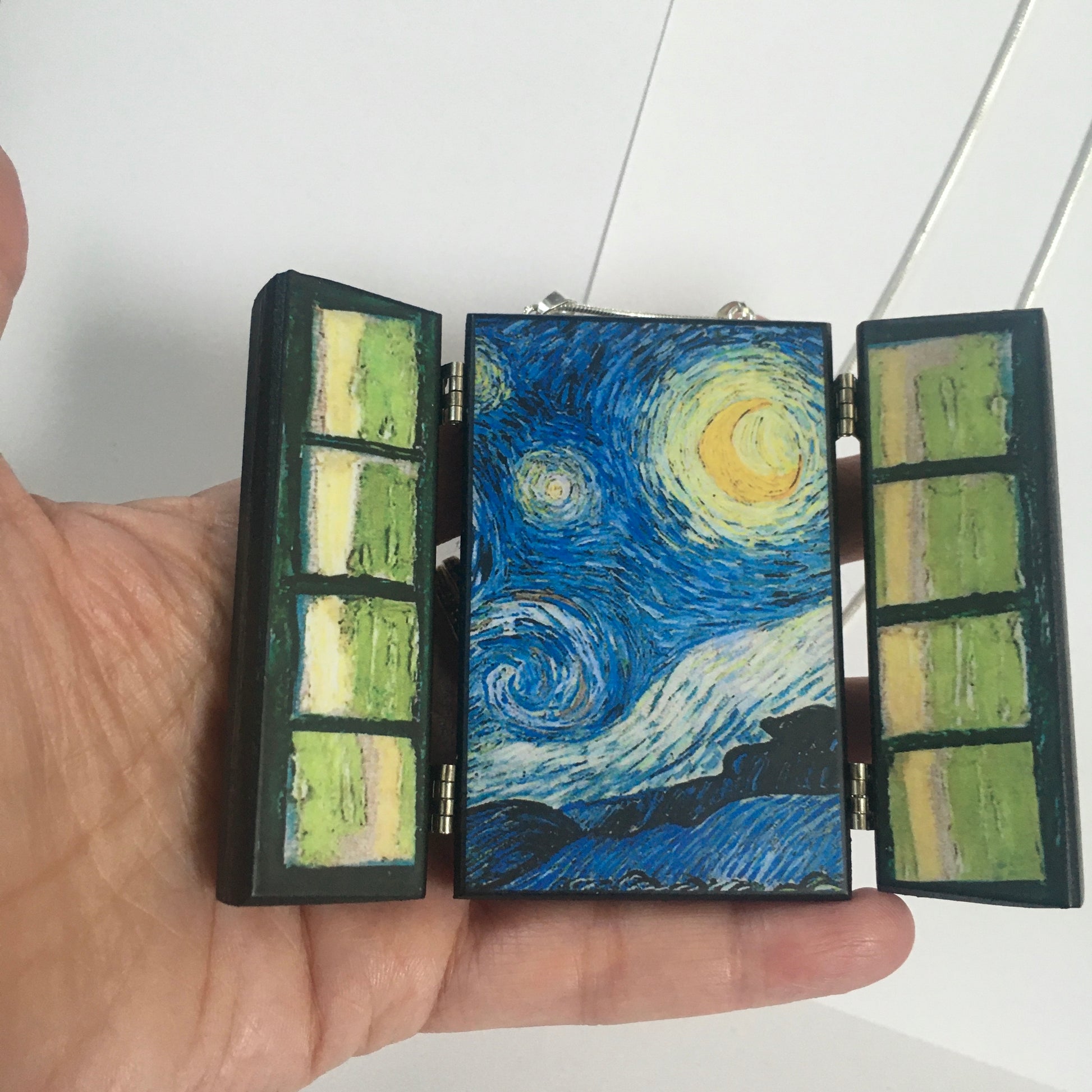 Fully functional, this statement pendant is made up of two doors inspired by the window from the post-impressionist painting "Bedroom at Arles", opening these two doors we find a detail of another famous painting by the artist Vincent Van Gogh: "Starry Night ".