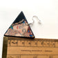 Klimt triangular earring nearby a rule that indicate the measurement of 4, 5 cm of his side. 