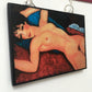 Amedeo Modigliani necklace handmade from sustainable wood by Obljewellery. The statement rectangular pendant with the painting of the nude female reclining on a red sofa on the blue cushion.