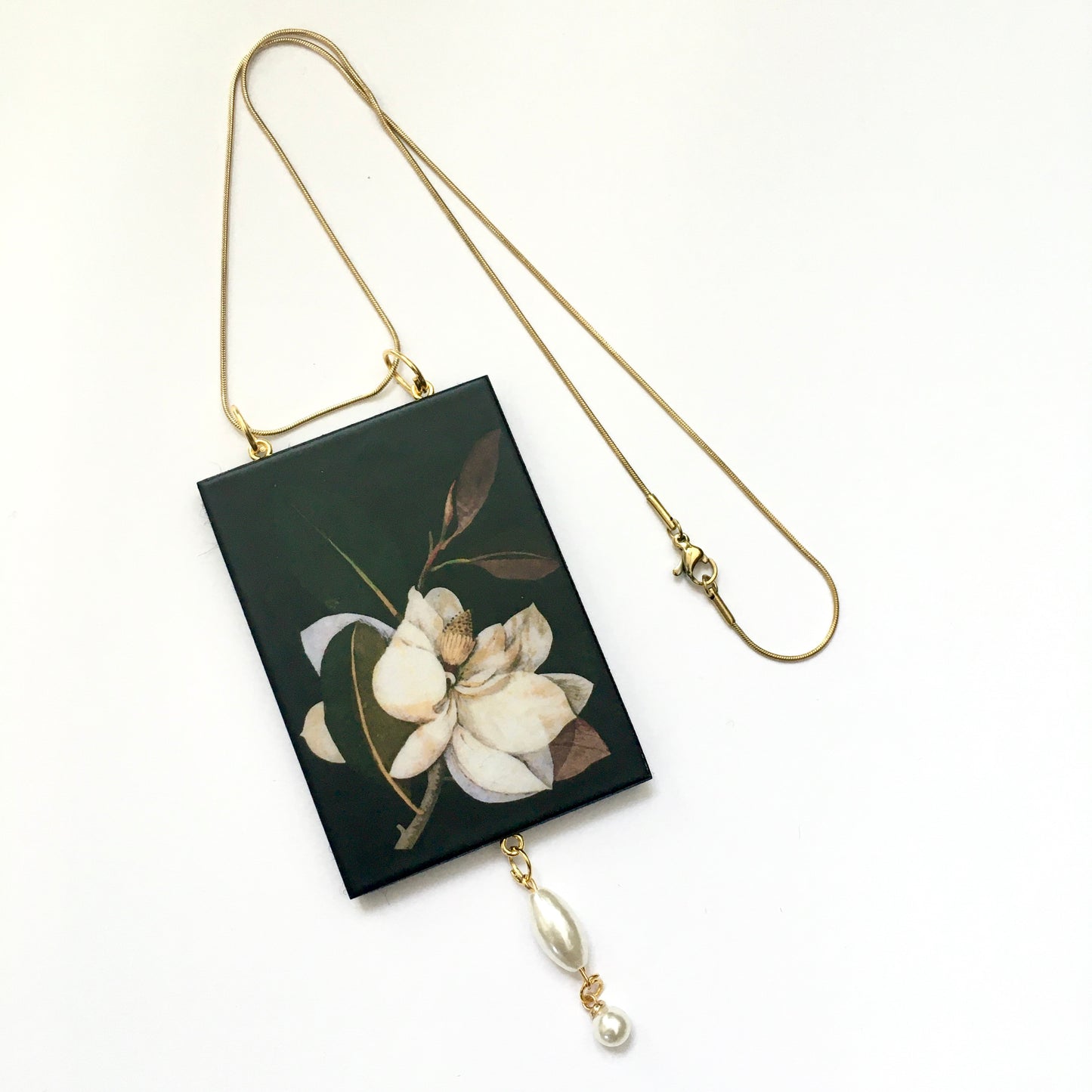Sustainable wood statement magnolia flower pendant with golden chain necklace and synthetic pearls.