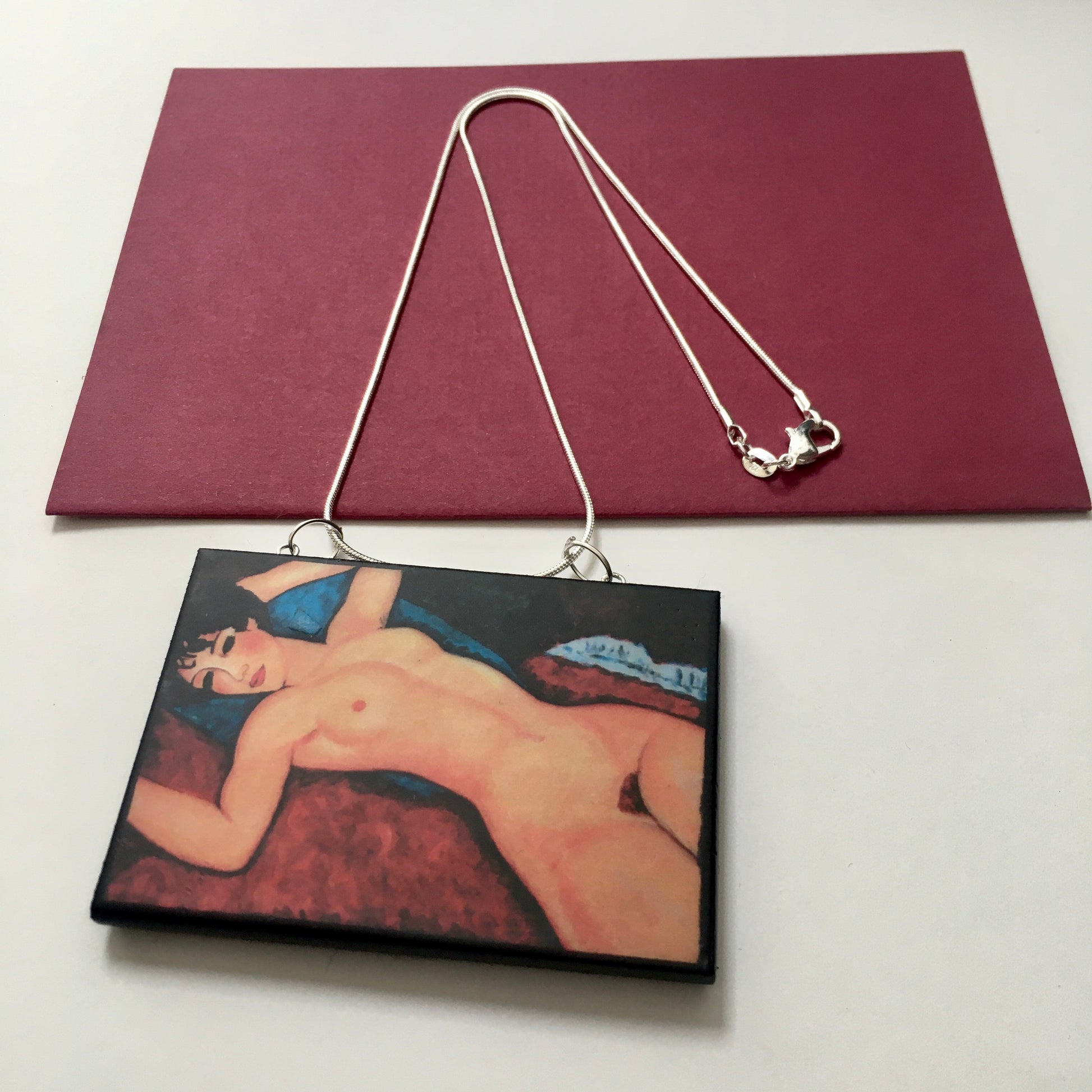 Amedeo Modigliani necklace handmade from sustainable wood by Obljewellery. The statement rectangular pendant with the painting of the nude female reclining on a red sofa on the blue cushion.